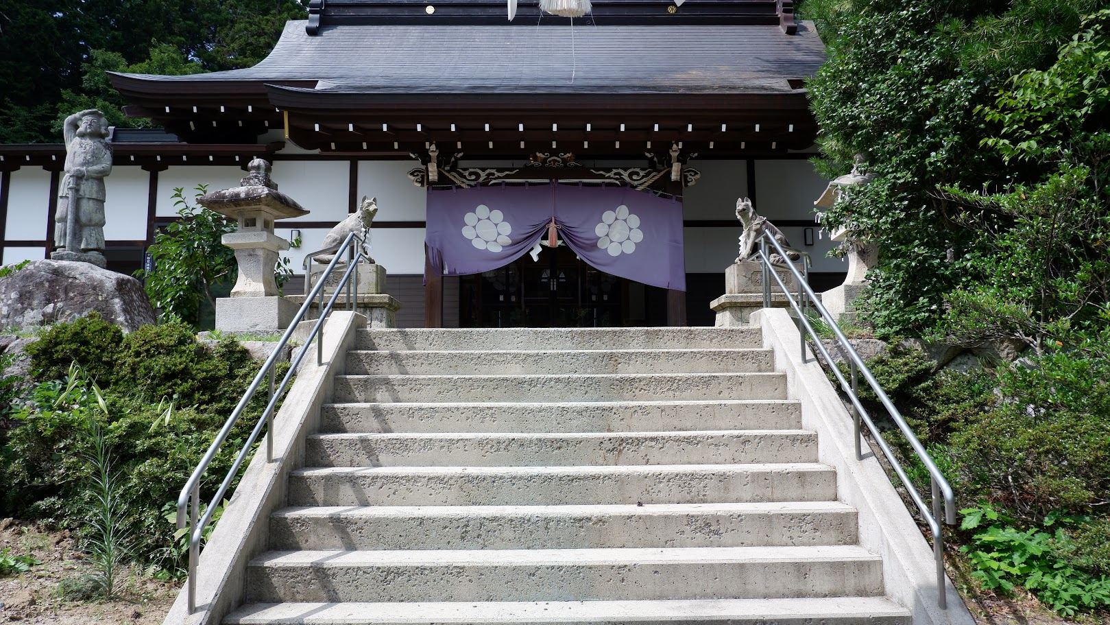 石段の上に構える拝殿と紫の幕